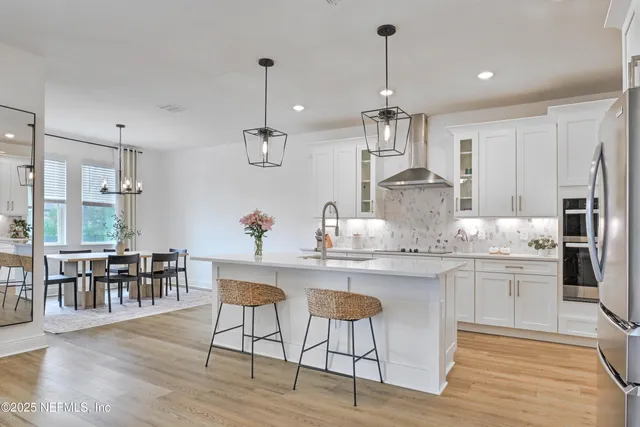 a kitchen with stainless steel appliances granite countertop a dining table chairs stove and white cabinets