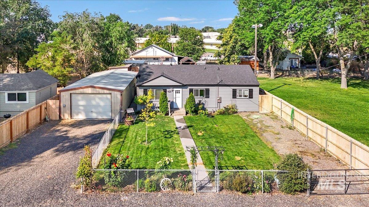 770 Riverside Avenue Grand View, ID 83624 - Photo 1 of 1 View of front facade with an outdoor structure, a fenced backyard, gravel driveway, and a garage