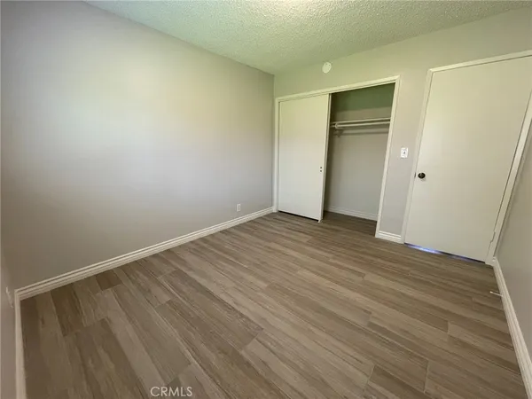 a view of an empty room with wooden floor and closet