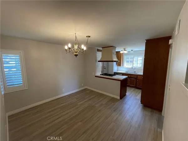 a view of kitchen and empty room with wooden floor