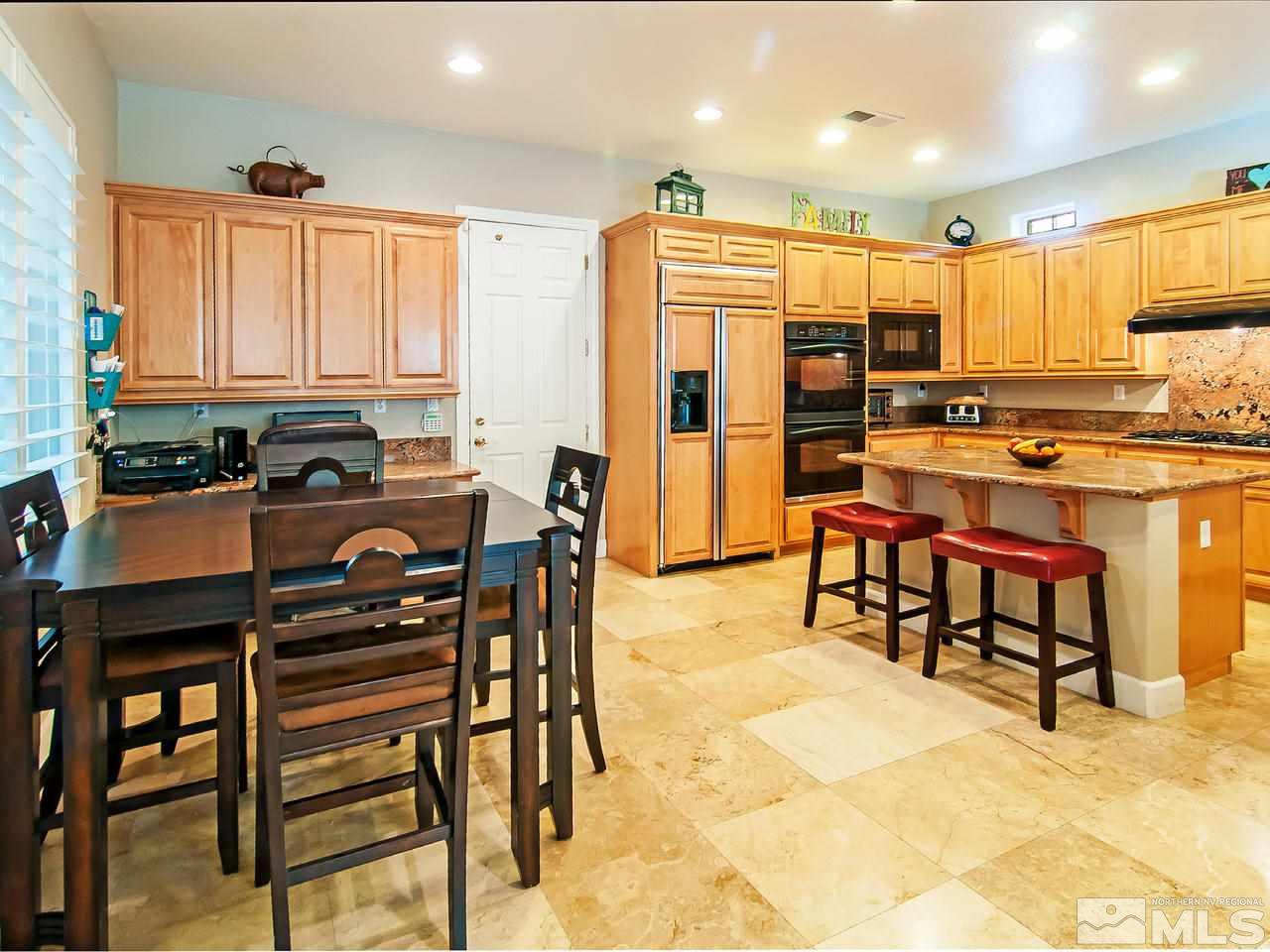 2690 Strathmore Court Reno, NV 89521 - Photo 9 of 25 a kitchen with stainless steel appliances kitchen island granite countertop a table chairs and a refrigerator