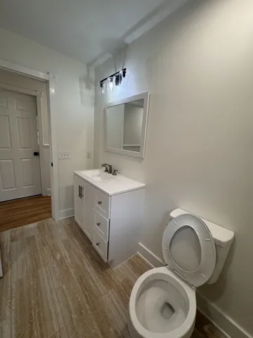 a bathroom with a toilet sink vanity granite and mirror