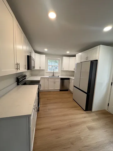 a kitchen with stainless steel appliances granite countertop a refrigerator sink and white cabinets