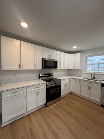 a kitchen with granite countertop white cabinets and white appliances