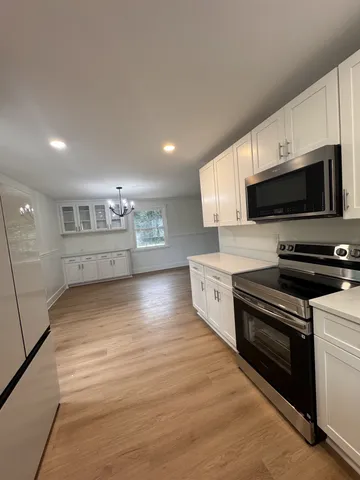 a kitchen with stainless steel appliances a stove a microwave and white cabinets