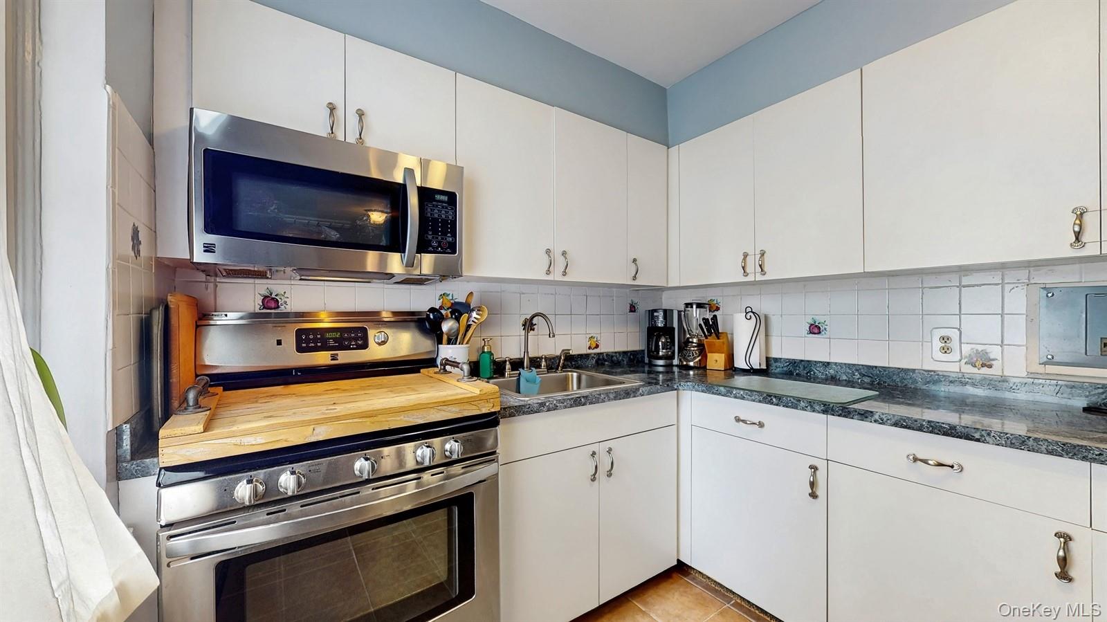 755 Bronx River Road, Unit 6C Bronxville, NY 10708 - Photo 13 of 22 a kitchen with stainless steel appliances a stove a microwave and cabinets