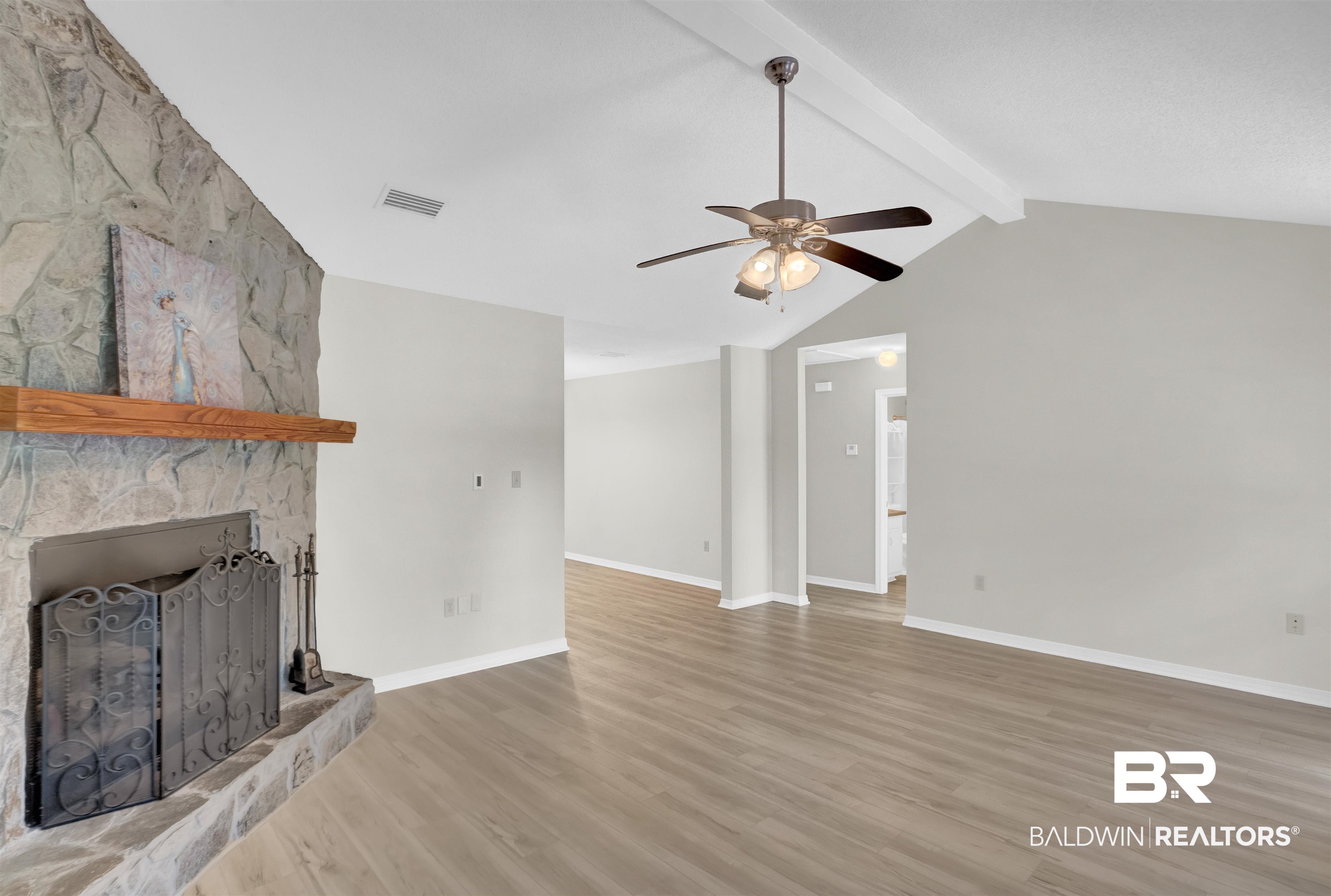 30871 Stanton Road Spanish Fort, AL 36527 - Photo 9 of 35 Unfurnished living room featuring ceiling fan, lofted ceiling with beams, wood-type flooring, and a fireplace