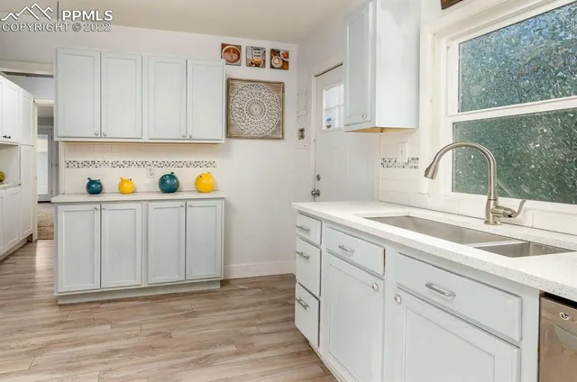 a kitchen with stainless steel appliances granite countertop a sink dishwasher a refrigerator and cabinets with wooden floor