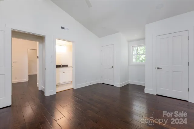 an empty room with wooden floor & windows and bathroom
