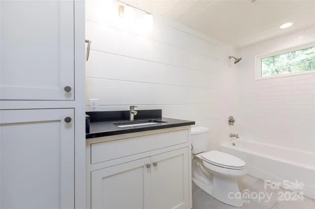 a bathroom with a granite countertop toilet sink and mirror