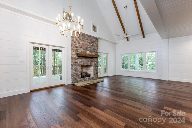 an empty room with wooden floor fireplace and windows