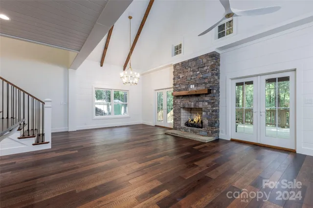 a view of an empty room with wooden floor fireplace and a window