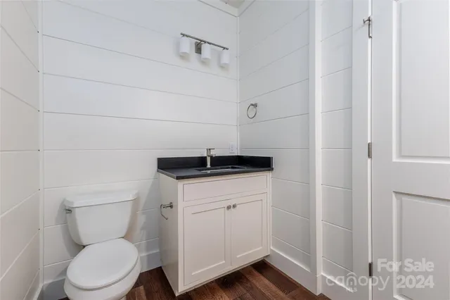 a bathroom with a toilet a sink and wooden floor