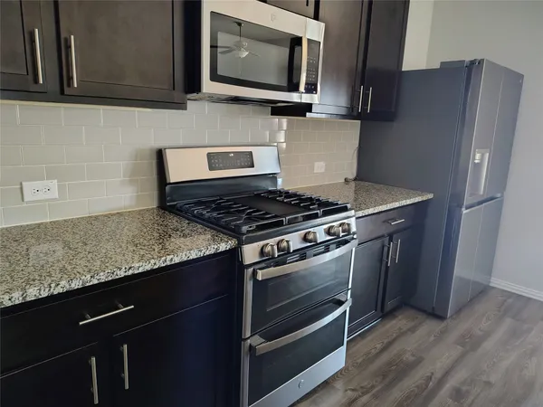 a kitchen with stainless steel appliances granite countertop a stove microwave and refrigerator
