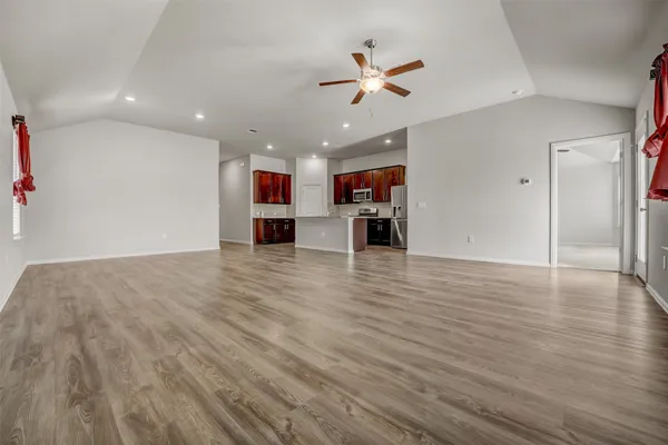 an empty space with kitchen view and wooden floor