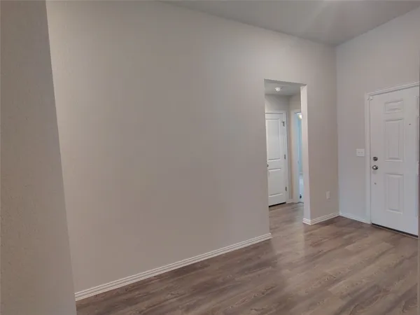 a view of an empty room with wooden floor and closet