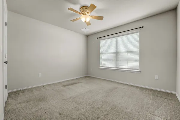an empty room with a window and a ceiling fan