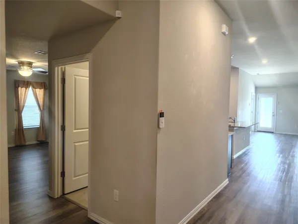 a view of a hallway with wooden floor and a bathroom