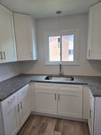 a kitchen with granite countertop white cabinets and sink