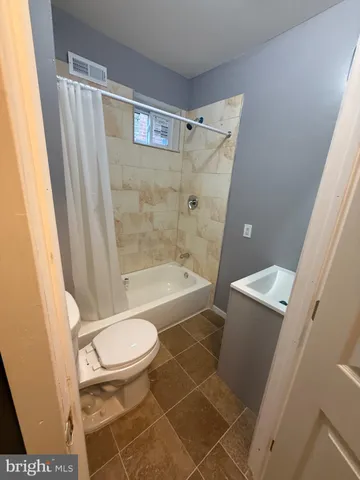 a bathroom with a granite countertop bathtub shower and toilet