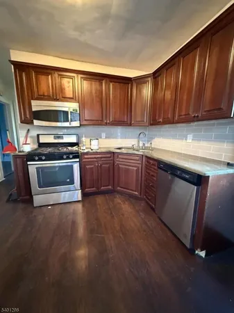 a kitchen with stainless steel appliances granite countertop wooden cabinets a stove top oven a sink and dishwasher