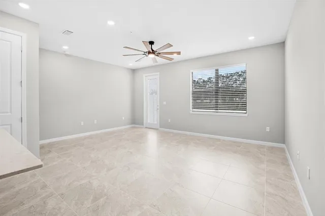 an empty room with windows and fan
