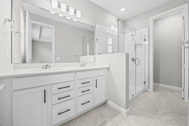 a bathroom with double vanity sink and shower