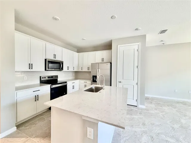 a kitchen with stainless steel appliances a refrigerator sink stove and white cabinets