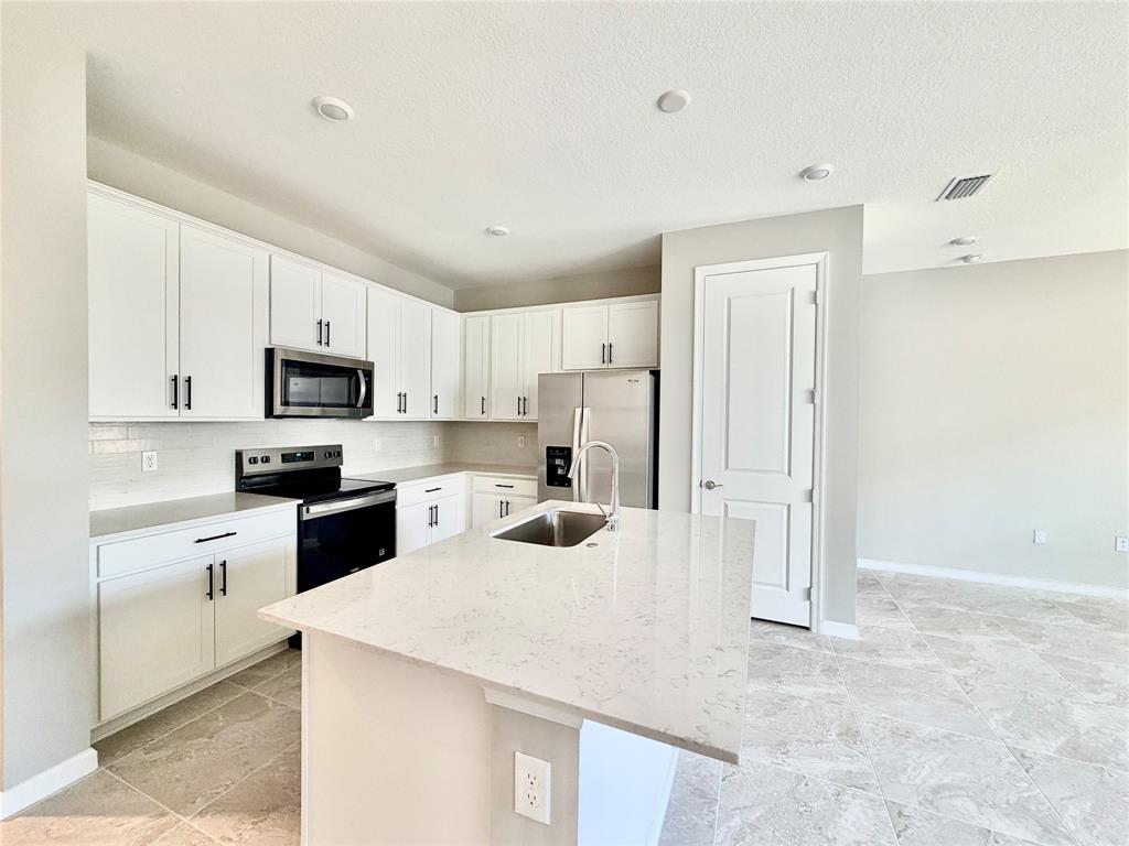 288 Southwest Sally Way Stuart, FL 34997 - Photo 3 of 22 a kitchen with stainless steel appliances a refrigerator sink stove and white cabinets