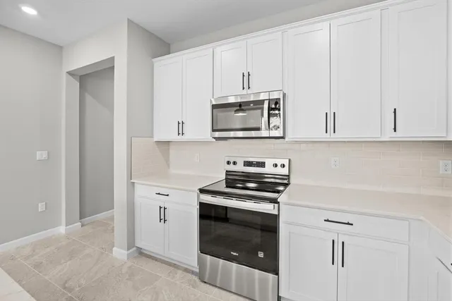 a kitchen with granite countertop white cabinets and stainless steel appliances