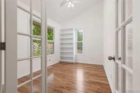 a view of an empty room with a window and wooden floor