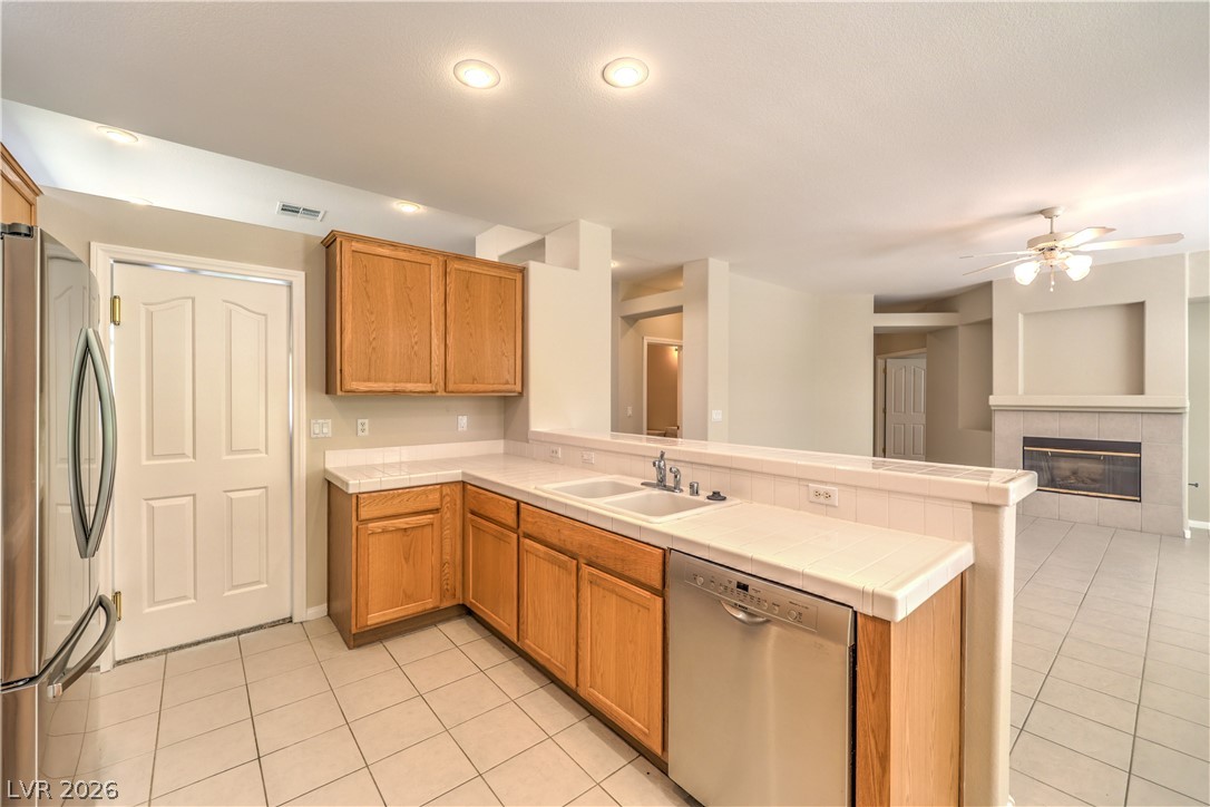 3713 Spring Shadow Road Las Vegas, NV 89129 - Photo 16 of 37 This kitchen showcases a functional layout with natural wood cabinetry and tile flooring, blending seamlessly into the adjacent living space.