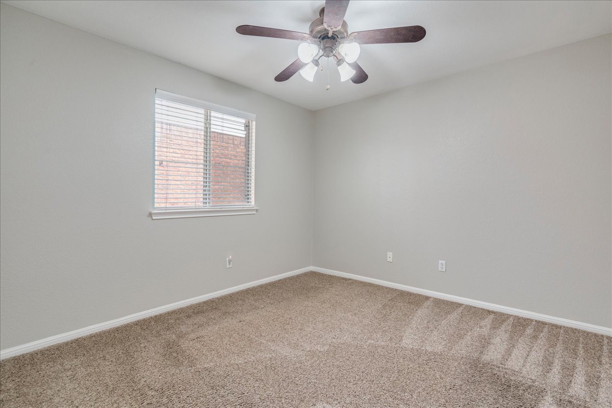 1151 Stone Rim Loop Buda, TX 78610 - Photo 23 of 36 Third bedroom features neutral-toned carpet and light gray walls, a window with blinds, and a ceiling fan with integrated lighting