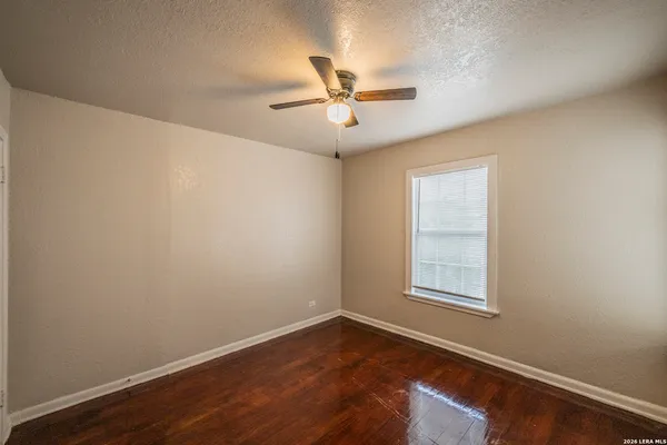 an empty room with wooden floor ceiling fan and windows