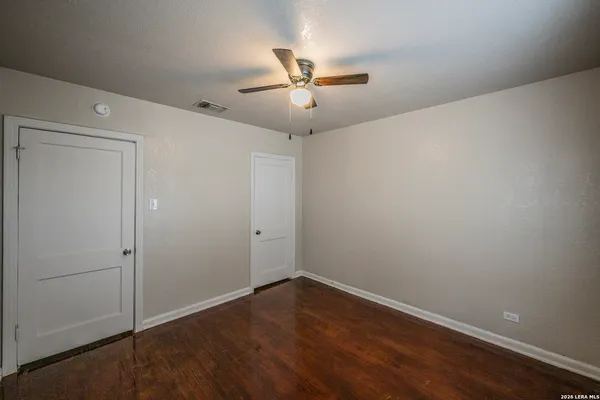 an empty room with wooden floor fan and windows