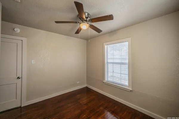an empty room with wooden floor closet and windows