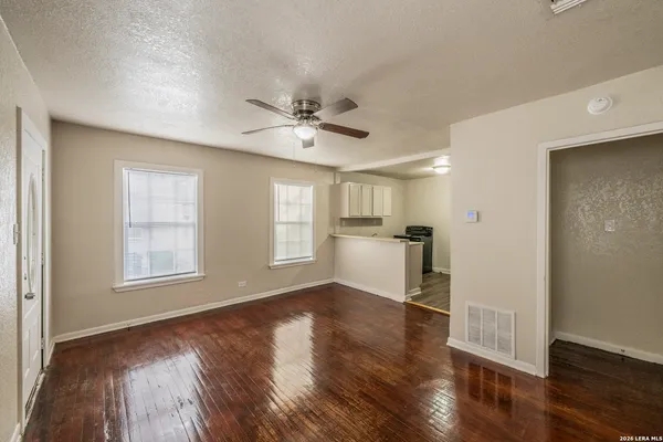 a view of an empty room with window and wooden floor