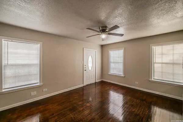 a view of an empty room with a window and wooden floor