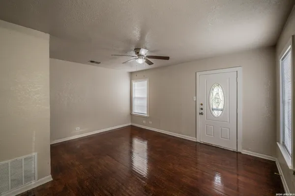 an empty room with wooden floor and windows