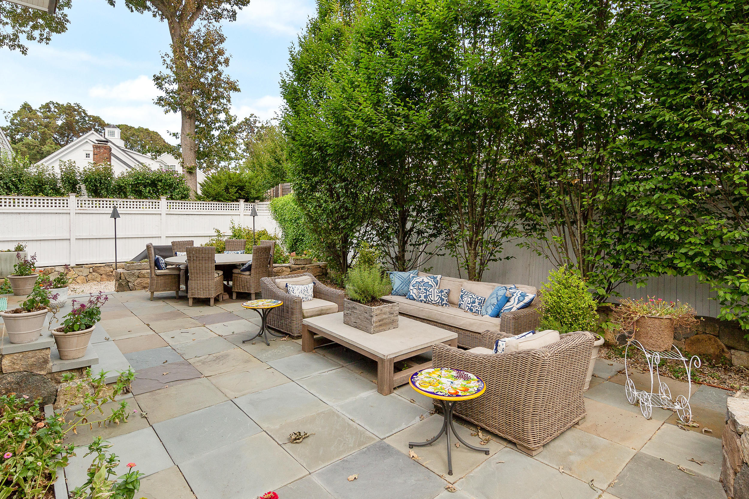 10 Juniper Road Rowayton, CT 06853 - Photo 20 of 28 a view of a patio with couches and chairs under an umbrella with large trees