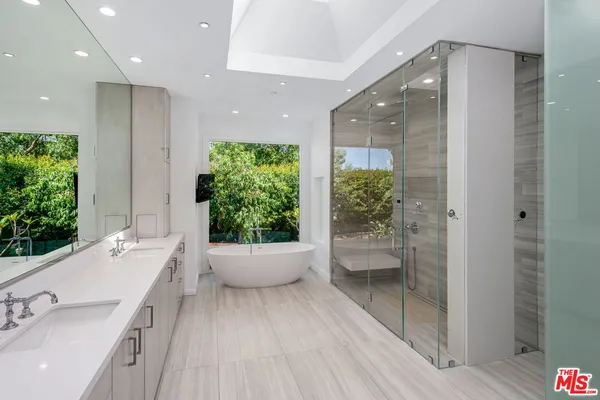 a spacious bathroom with a double vanity sink a large mirror and shower