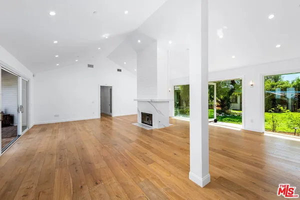 an empty room with wooden floor and fireplace