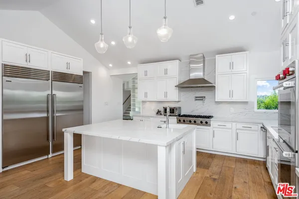 a large kitchen with kitchen island a stove a sink a oven and a refrigerator