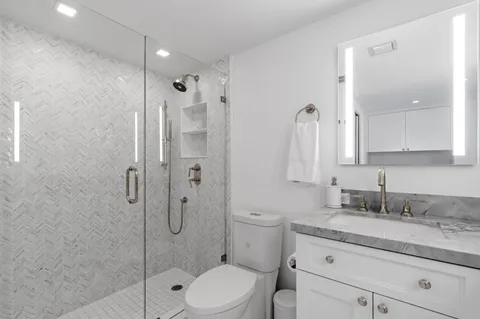 a bathroom with a granite countertop double vanity sink and mirror