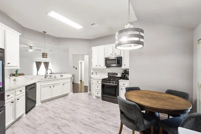 a kitchen with stainless steel appliances a stove a sink dishwasher a stove a refrigerator with a dining table and chairs