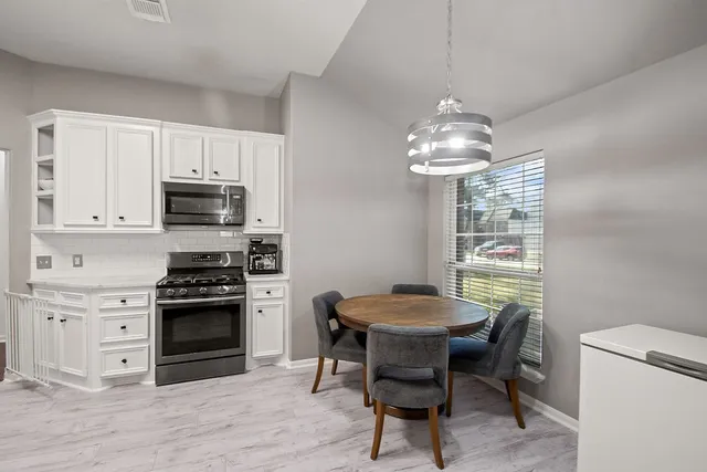 a kitchen with stainless steel appliances a dining table chairs and granite counter tops