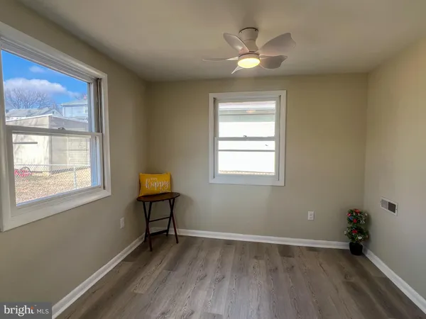 a view of an empty room with window and wooden floor