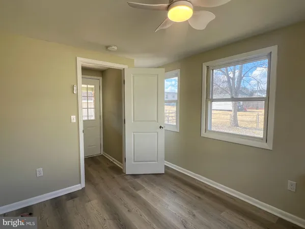 a view of an empty room with window and wooden floor