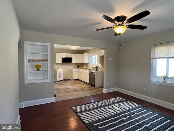 a living room with stainless steel appliances kitchen island granite countertop furniture and a wooden floor