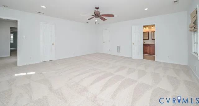 an empty room with chandelier fan and windows